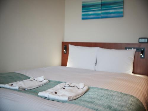 a bed with two towels on top of it at THE GRAND HOTEL GINOWAN in Ginowan