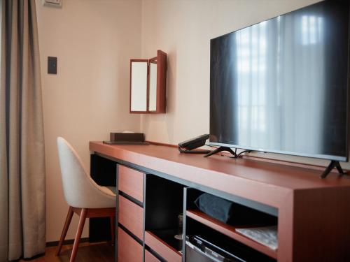 a hotel room with a large flat screen tv on a desk at THE GRAND HOTEL GINOWAN in Ginowan