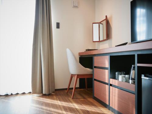 a room with a desk and a chair next to a window at THE GRAND HOTEL GINOWAN in Ginowan