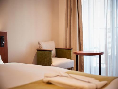 a hotel room with a bed and a chair and a window at THE GRAND HOTEL GINOWAN in Ginowan