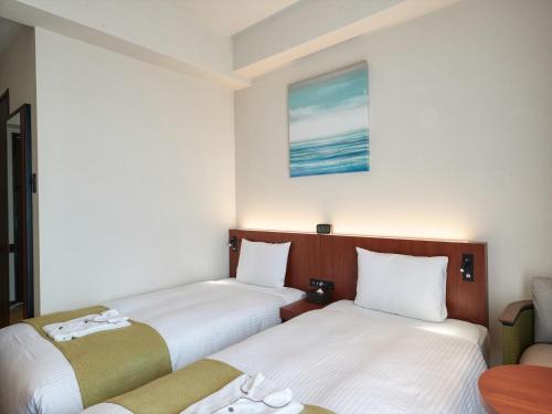 two beds in a small room with a table at THE GRAND HOTEL GINOWAN in Ginowan