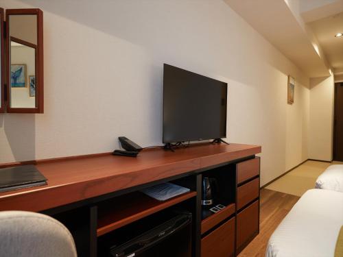 a room with a desk with a television on it at THE GRAND HOTEL GINOWAN in Ginowan