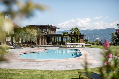 een zwembad in een tuin met een huis bij Hotel Ansitz Rungghof in Appiano sulla Strada del Vino