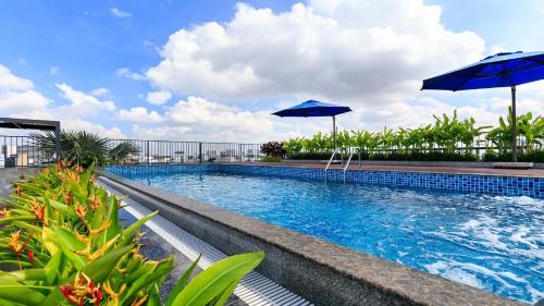 a swimming pool with two umbrellas on top of it at DHTS Business Hotel & Apartment in Ho Chi Minh City