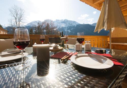a table with glasses of red wine on a balcony at Panoramapark Soleil Chalet B in Wengen