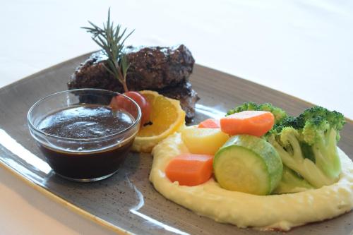 a plate of food with meat and vegetables and a sauce at Saraya Corniche Hotel in Doha