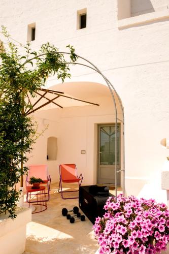 a patio with pink flowers and two chairs at Masseria D'Erchia in Monopoli