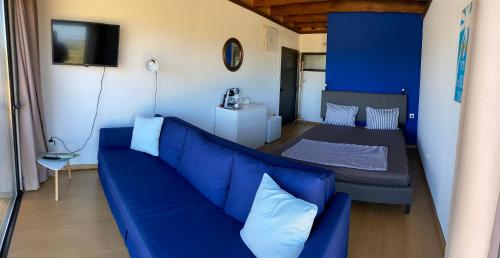 a living room with a blue couch and a bed at Phaedra in Elafonisi
