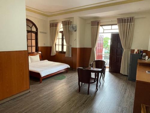 1 dormitorio con 1 cama, mesa y sillas en Khách sạn Mekong Star en Vĩnh Long