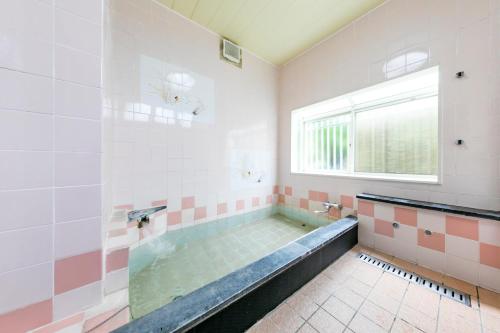 a large bathroom with a tub with a window at Guesthouse leaf in Hokuto