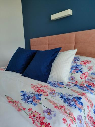 a bed with blue and white sheets and blue pillows at Apartamenty Mistral in Jastarnia