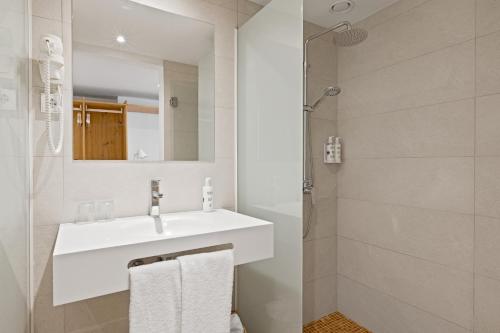 a white bathroom with a sink and a shower at Palmanova Beach Apartments by TRH in Palmanova