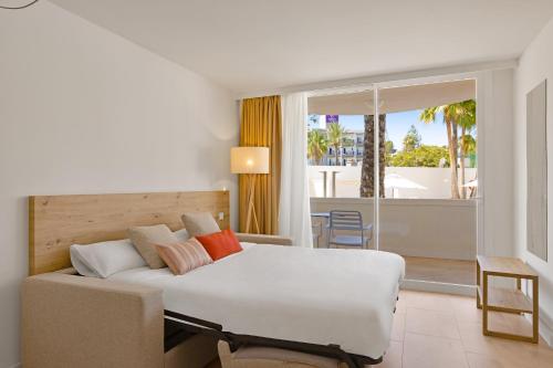 a bedroom with a bed and a couch and a balcony at Palmanova Beach Apartments by TRH in Palmanova