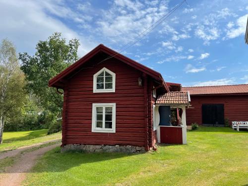 a small red house with a grass yard at Dalastuga med tillgång till badplats in Leksand