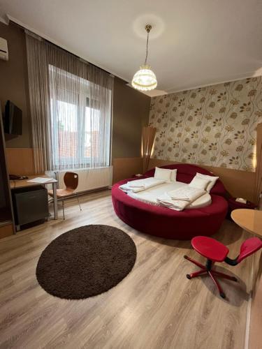 ein Schlafzimmer mit einem großen roten Bett in einem Zimmer in der Unterkunft Korona Panzió in Mátészalka