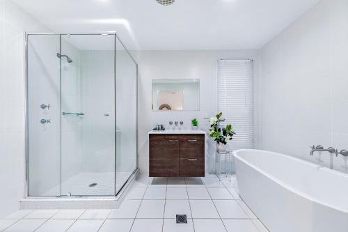 bagno bianco con vasca e doccia di MANDALAY ESCAPE, SECLUSION & SERENITY WITH A POOL ad Airlie Beach