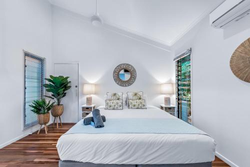 a white bedroom with a large bed and windows at MANDALAY ESCAPE, SECLUSION & SERENITY WITH A POOL in Airlie Beach