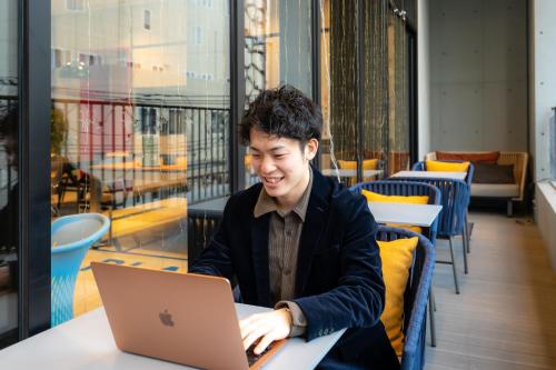 a man sitting at a table with a laptop at lyf Tenjin Fukuoka in Fukuoka