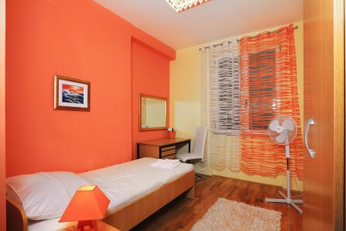 a bedroom with orange walls and a bed and a window at Apartment Split 17386a in Split