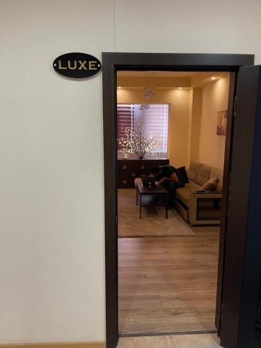 a door to a living room with a person sitting on a couch at Flamingo in Dushanbe