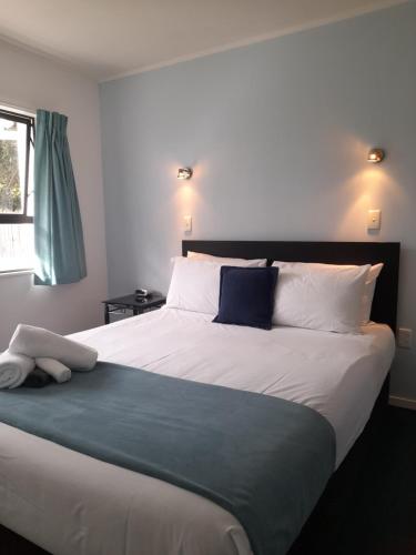 een slaapkamer met een groot bed met blauwe en witte kussens bij Marlin Court Motel in Paihia
