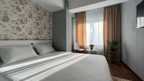 a bedroom with a large bed and a floral wall at Ballade Apartment in Iaşi