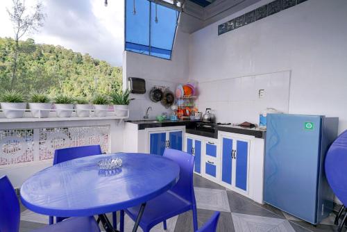 RedDoorz near Pantai Pandan Sibolga في Halangan: مطبخ مع طاولة زرقاء وكراسي أرجوانية