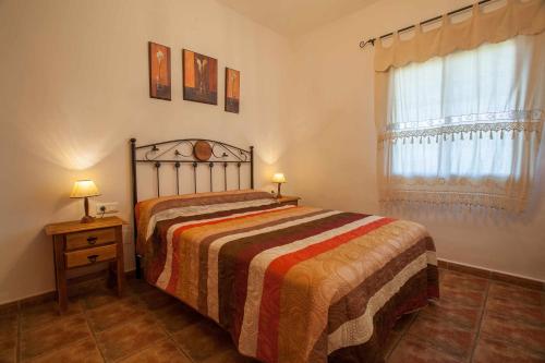 a bedroom with a bed with a striped blanket and a window at Casa Mirador Las claras Con Piscina privada jardin y AireAcodicionado in Iznate