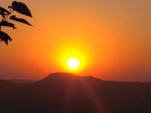 una puesta de sol en la cima de una montaña con el sol en Omkar Agro Tourism & Resort, en Mahabaleshwar