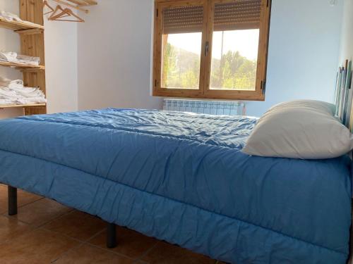 a bed with a blue comforter and a window at Casas Rurales La Trufa Madre Casa 2 in Vega del Codorno