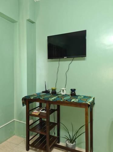 Habitación con mesa y TV en la pared. en Affordable Transient in Valley Golf near Emperor Events Place, en Cainta