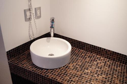 a bathroom with a white sink on a tiled floor at Hotel Amala in Mexico City
