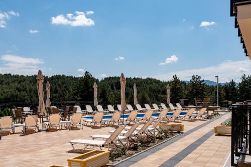 a row of lounge chairs and umbrellas on a patio at Monix Palace Zlatibor in Zlatibor