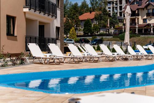 a row of lounge chairs next to a swimming pool at Monix Palace Zlatibor in Zlatibor