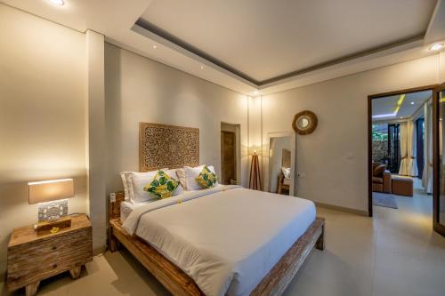 a bedroom with a large white bed and a table at Green Oasis Private Villa in Ubud