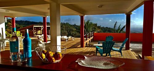 una mesa de madera con botellas y vasos en el porche en Villa CosaRoé Martinique Piscine et superbe vue mer en Rivière-Salée