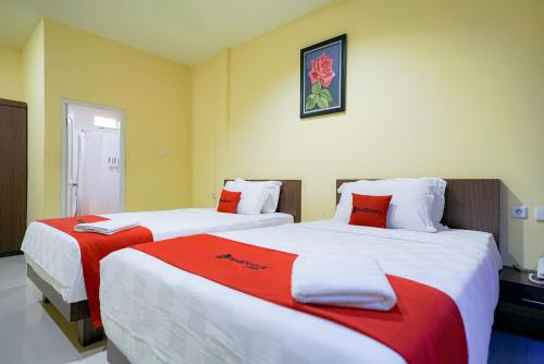 a bedroom with two beds with red and white sheets at RedDoorz Plus @ Jalan FL Lumban Tobing Sibolga in Sibolga