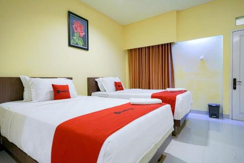 um quarto de hotel com duas camas com lençóis vermelhos e brancos em RedDoorz Plus @ Jalan FL Lumban Tobing Sibolga em Sibolga