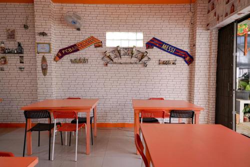 a dining room with orange tables and chairs and a brick wall at RedDoorz Plus @ Jalan FL Lumban Tobing Sibolga in Sibolga