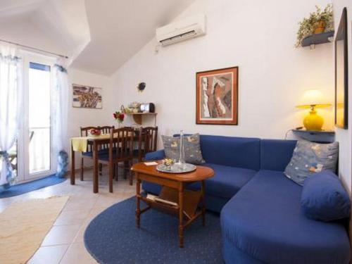 ein Wohnzimmer mit einem blauen Sofa und einem Tisch in der Unterkunft Family friendly seaside apartments Krapanj, Sibenik - 18004 in Šibenik