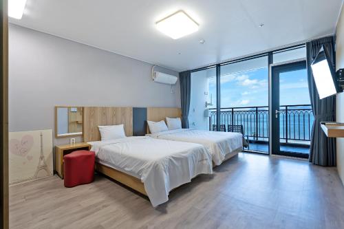 a hotel room with two beds and a balcony at Gold Beach Resort in Yeosu