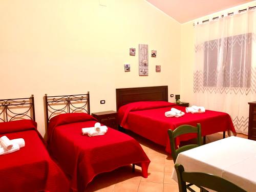 a bedroom with two beds with red sheets and white towels at Green Park Hotel & Residence in Bagnara Calabra