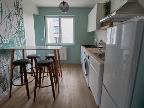 uma cozinha com um frigorífico branco, uma mesa e bancos em *Green Organic* Balcon & Garage em Clermont-Ferrand