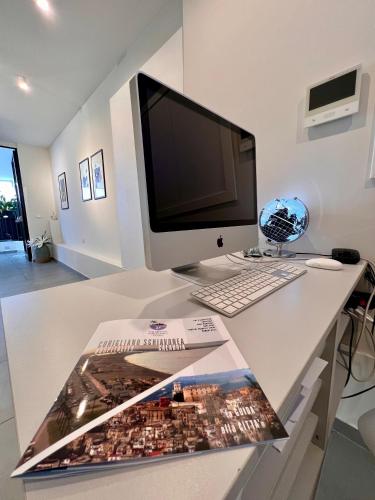 a desk with a computer monitor and a magazine on it at Agathè Luxury Bed and Breakfast in Marina di Schiavonea