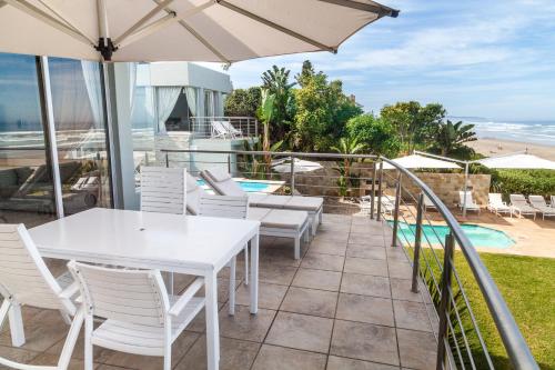 a patio with a white table and chairs and an umbrella at Ti’amo in Wilderness