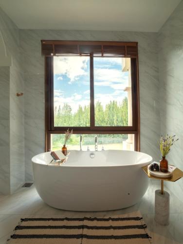 a large white tub in a bathroom with a window at Toscana Valley Castello Della Valle in Mu Si