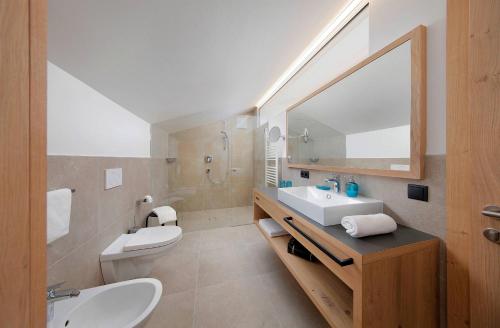 uma casa de banho com um lavatório, um WC e um espelho. em Appartement-Hotel Anthea em Tirolo