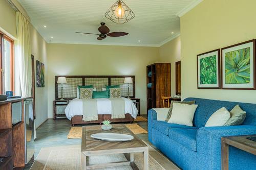 a living room with a blue couch and a bed at Hilton Bush Lodge & Function Venue in Hilton