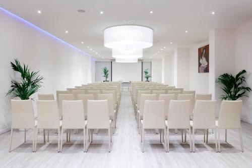 a conference room with a long table and white chairs at Hotel Palma Bellver , Affiliated by Meliá in Palma de Mallorca