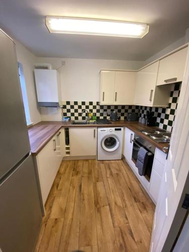 a small kitchen with a washer and dryer in it at Spacious 3 bed flat a stones throw from the beach in Pakefield